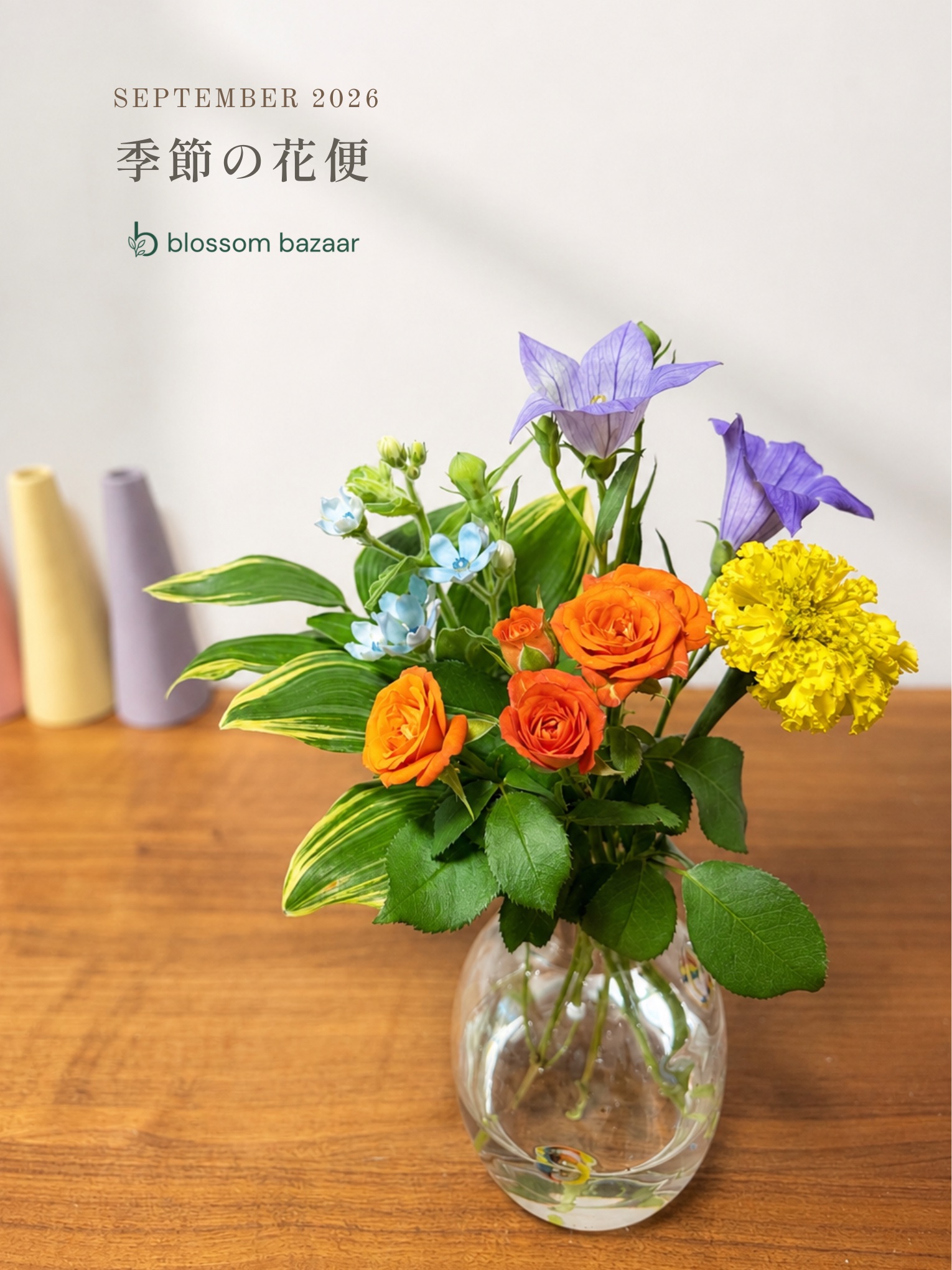 オレンジのバラと紫や黄色の花を合わせた季節の花便